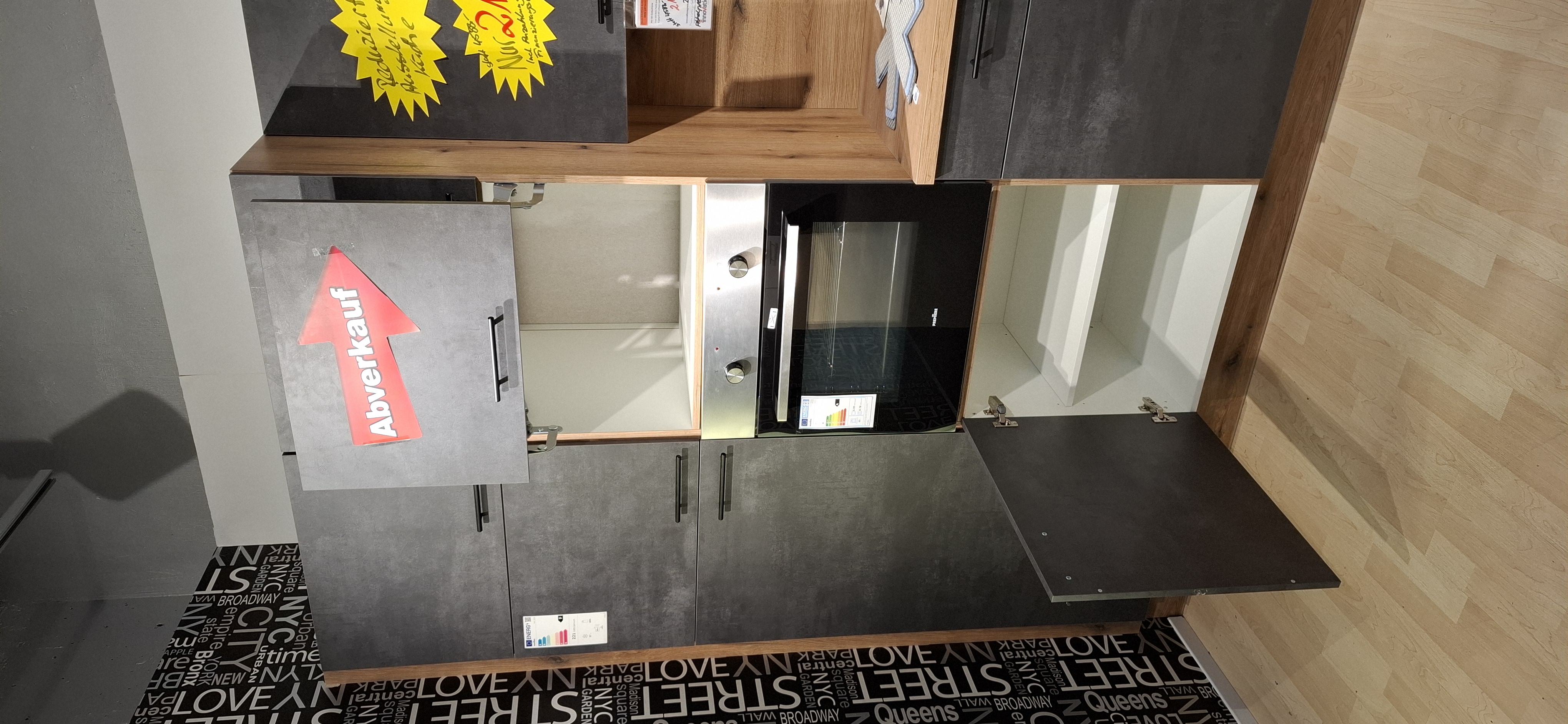 Blick in den geöffneten Unterschrank unterhalb des Backofens und in die geöffnete Lifttür oberhalb des Backofens