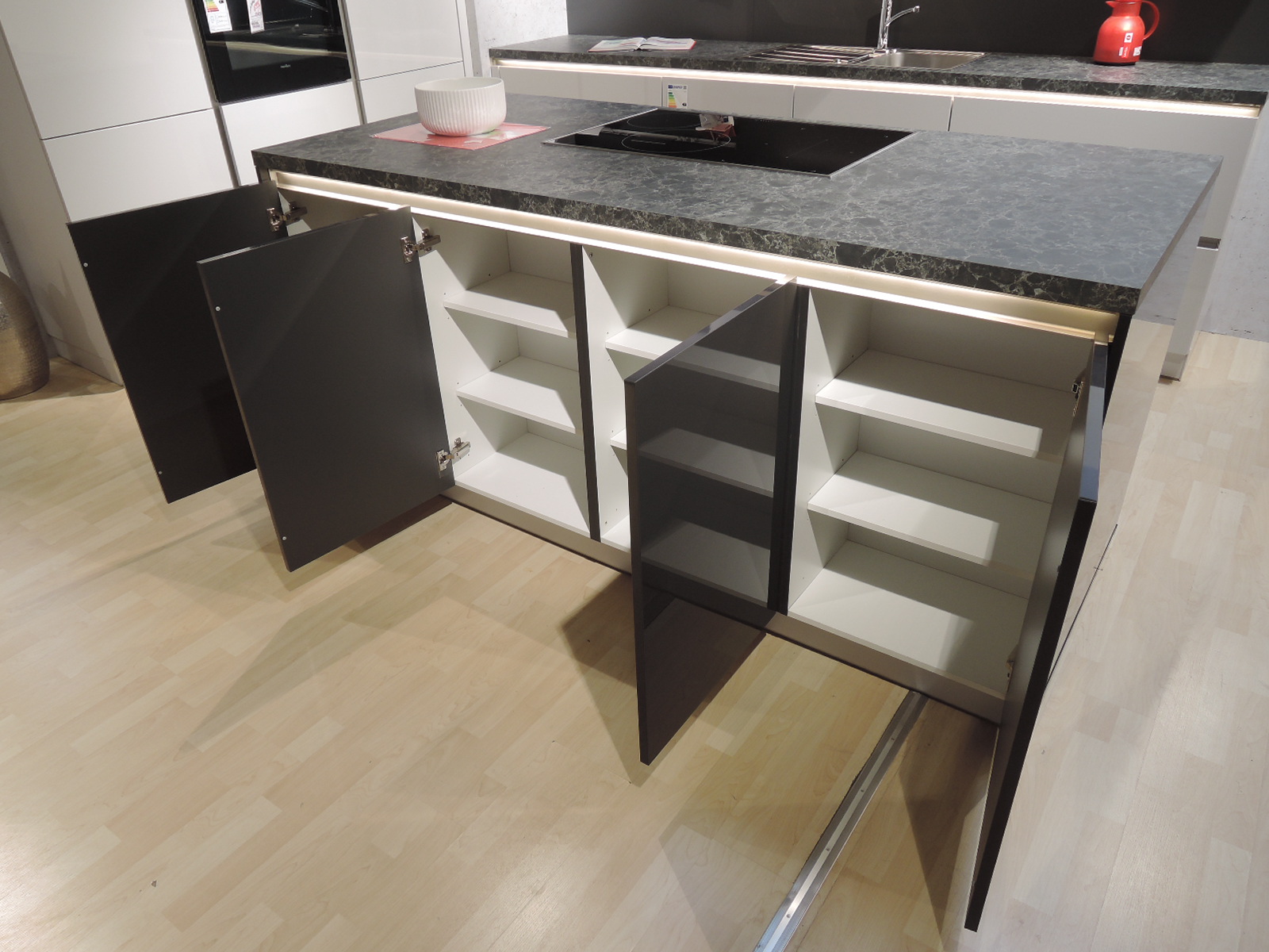 Direktansicht auf die Rückseite der Kochinsel mit geöffneten Unterschränken