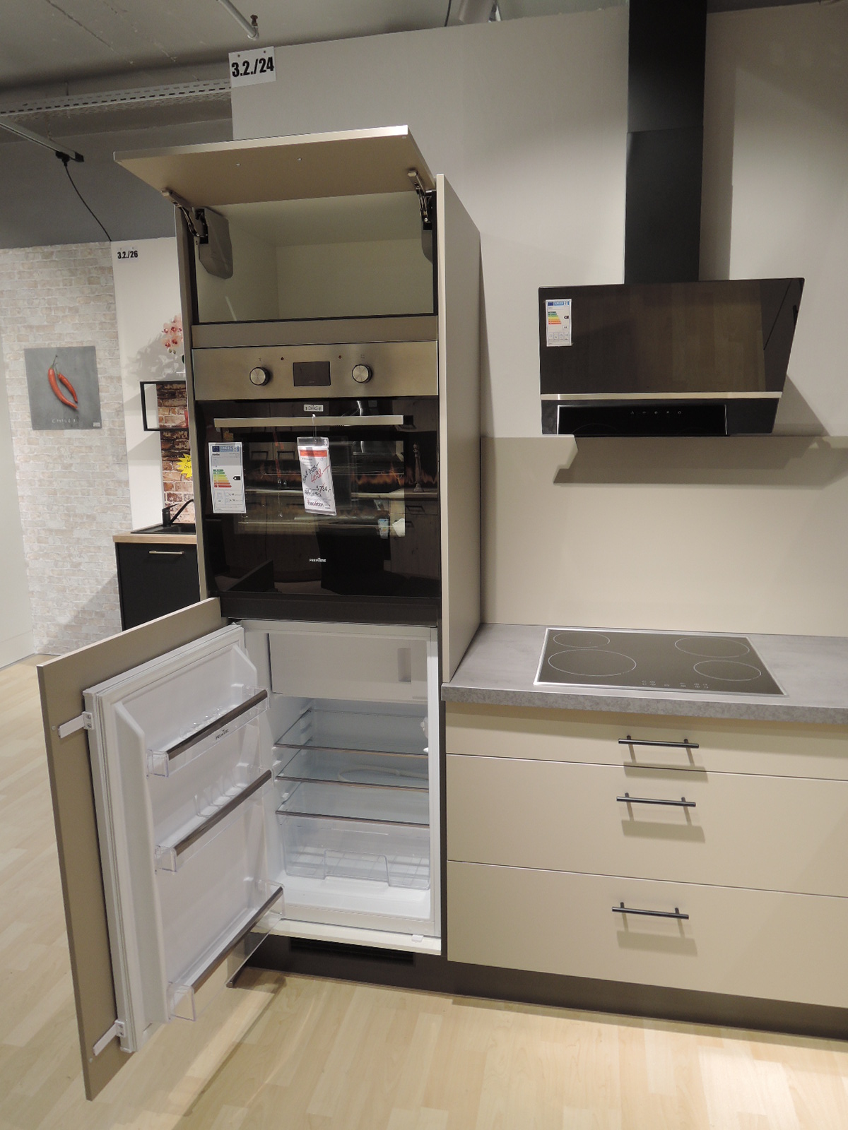 Blick in den geöffneten Einbau-Kühlautomat und geöffneter Klappe oberhalb vom Backofen