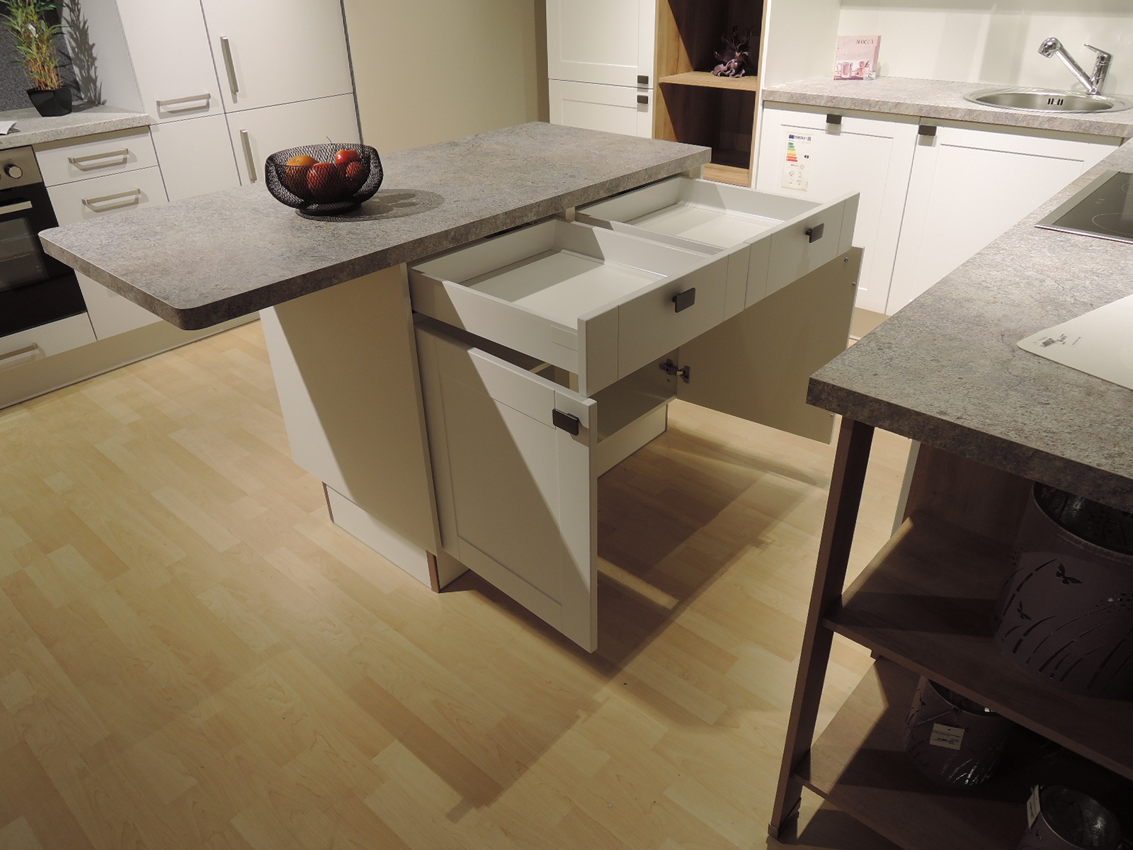 Blick auf die Vorderseite der Arbeitsinsel mit geöffneten Schubladen und Unterschränken