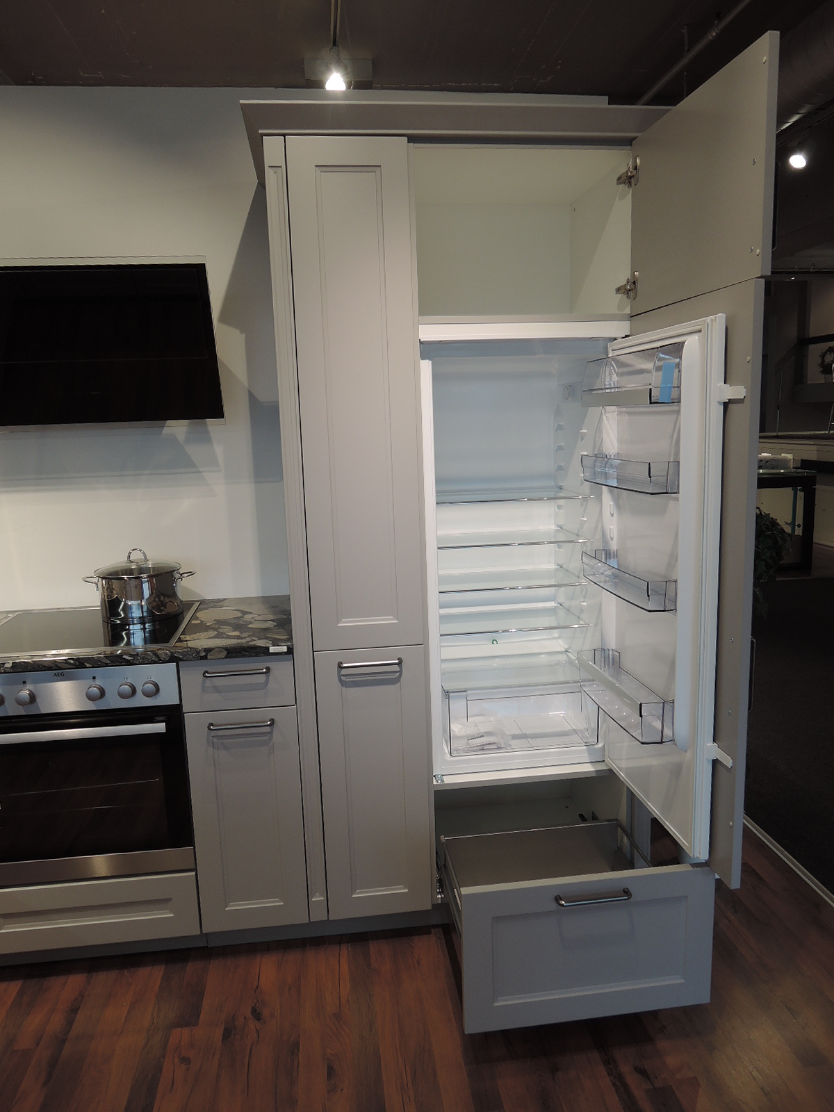 Blick in den geöffneten Einbau-Kühlautomat mit darunterliegendem Auszug und Fach über dem Kühlgerät