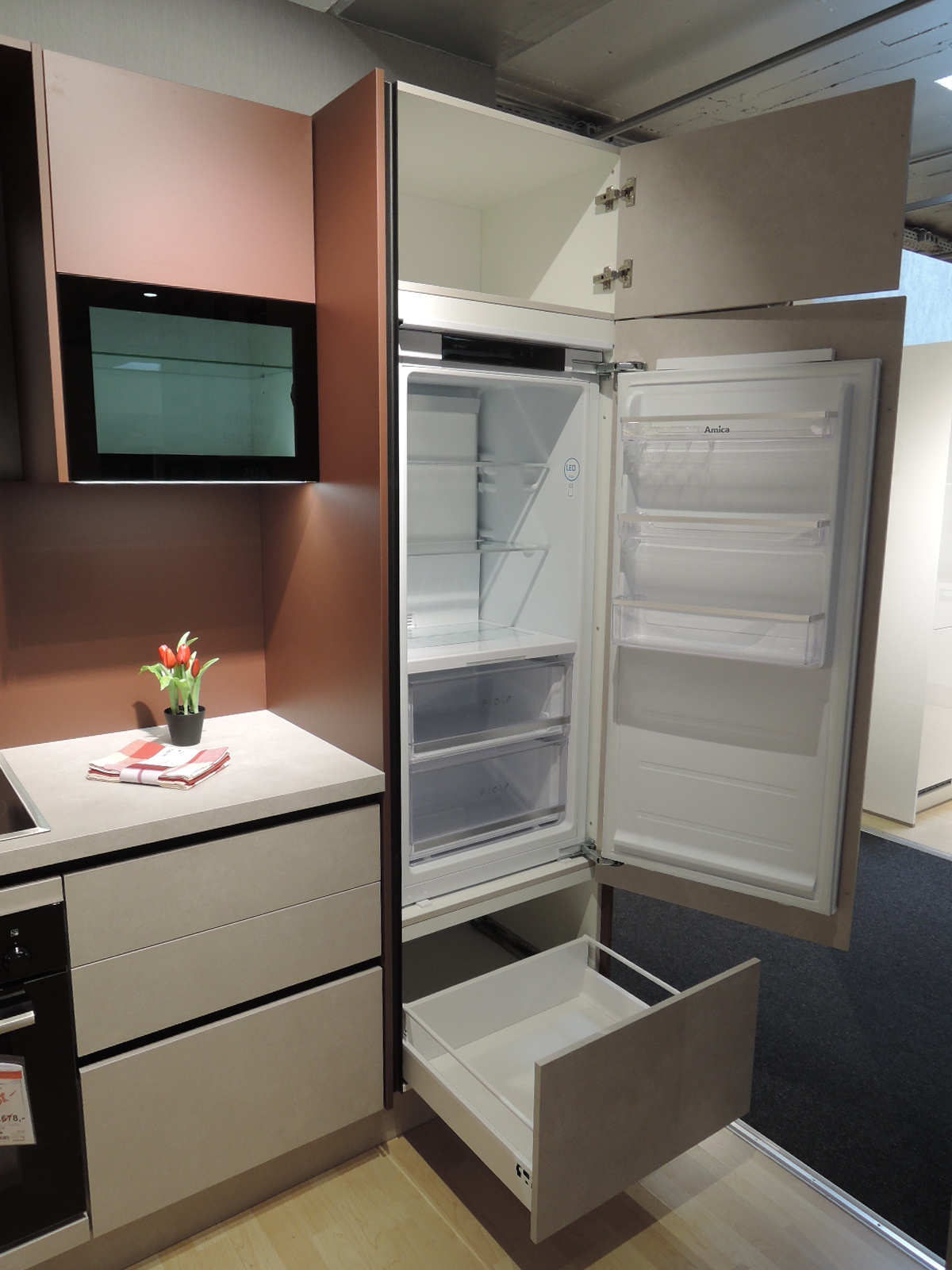 Blick in den geöffneten Einbau-Kühlschrank mit darunterliegendem geöffneten Auszug