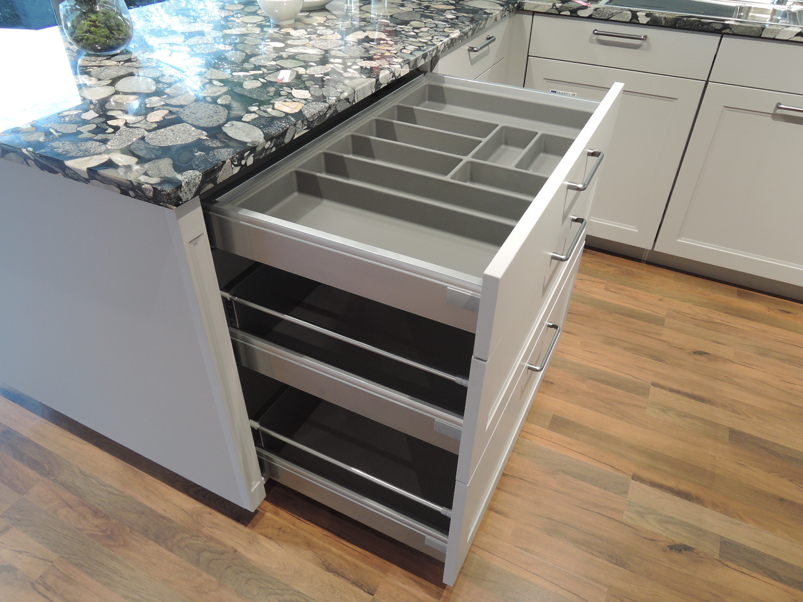Blick in die geöffnete Schublade mit Besteckeinsatz und in die geöffneten Auszüge unterhalbe 
