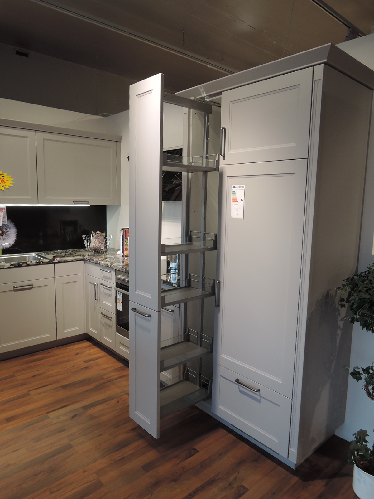 Seitlichen Blick in den geöffneten Apothekerschrank links vom Einbau-Kühlautomat